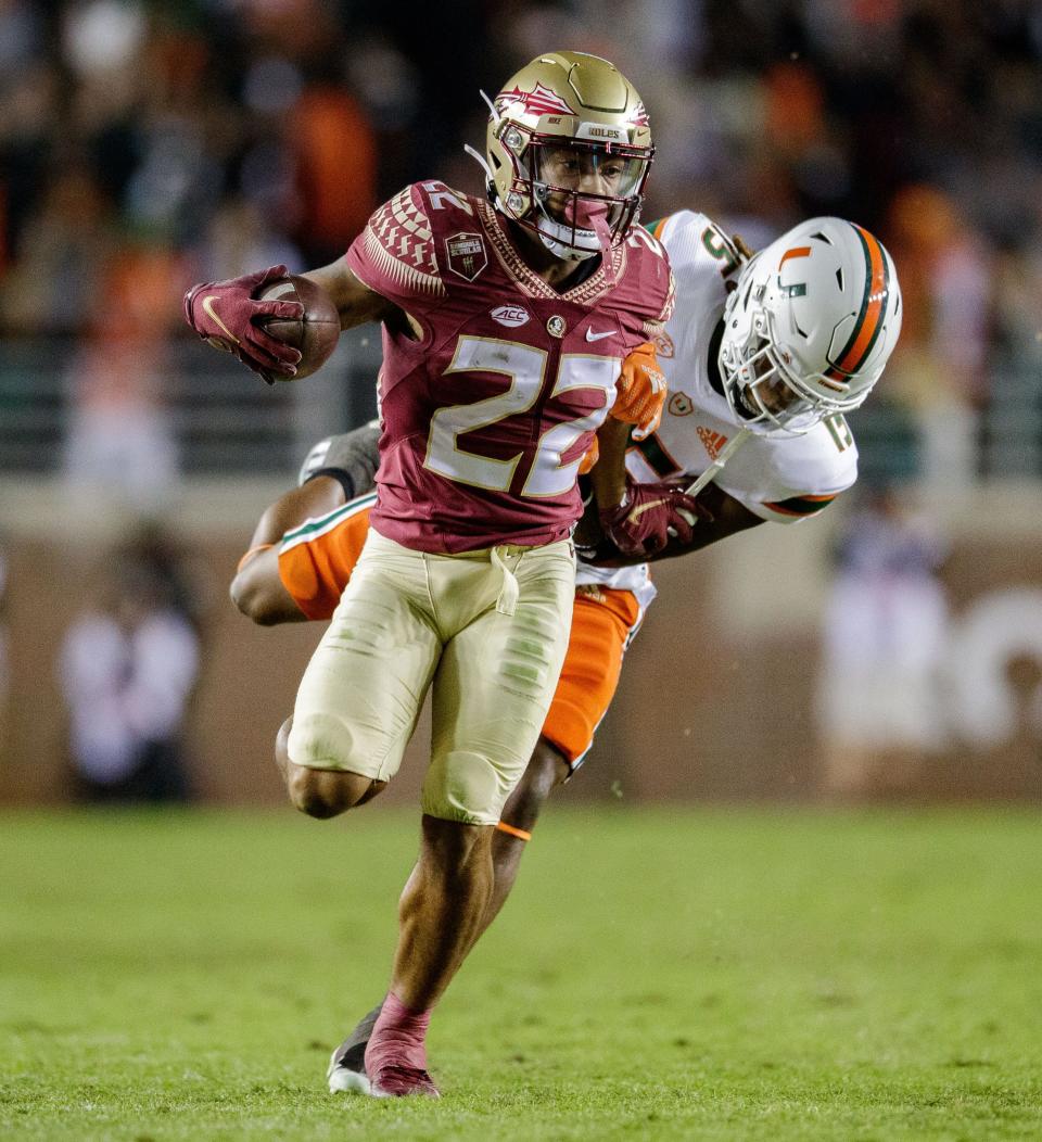 Florida State Seminoles wide receiver Ja'Khi Douglas (22) tries to outrun a tackle. The Florida State Seminoles defeated the Miami Hurricanes 31-28 Saturday, Nov. 13, 2021.