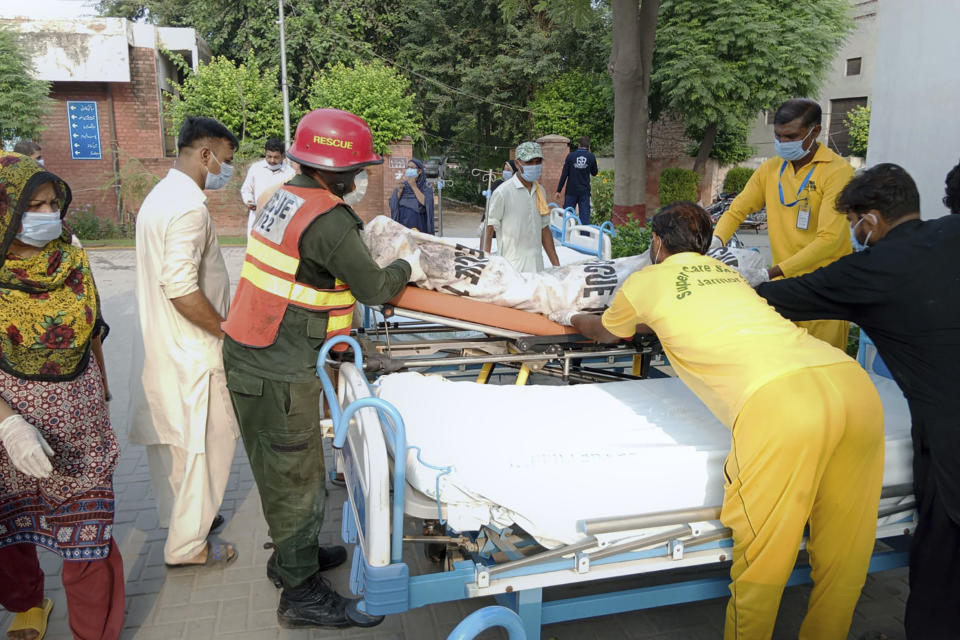 In this photo released by the Rescue 1122 Emergency Department, hospital staff and rescue workers carry a victim of a bus accident into a hospital in Pindi Bhattian, Pakistan, Sunday, Aug. 20, 2023. A bus in Pakistan caught fire after hitting a van parked on the shoulder of an intercity highway in eastern Punjab province, killing multiple people and injuring others, police and rescue officials said Sunday. (Rescue 1122 Emergency Department vis AP)