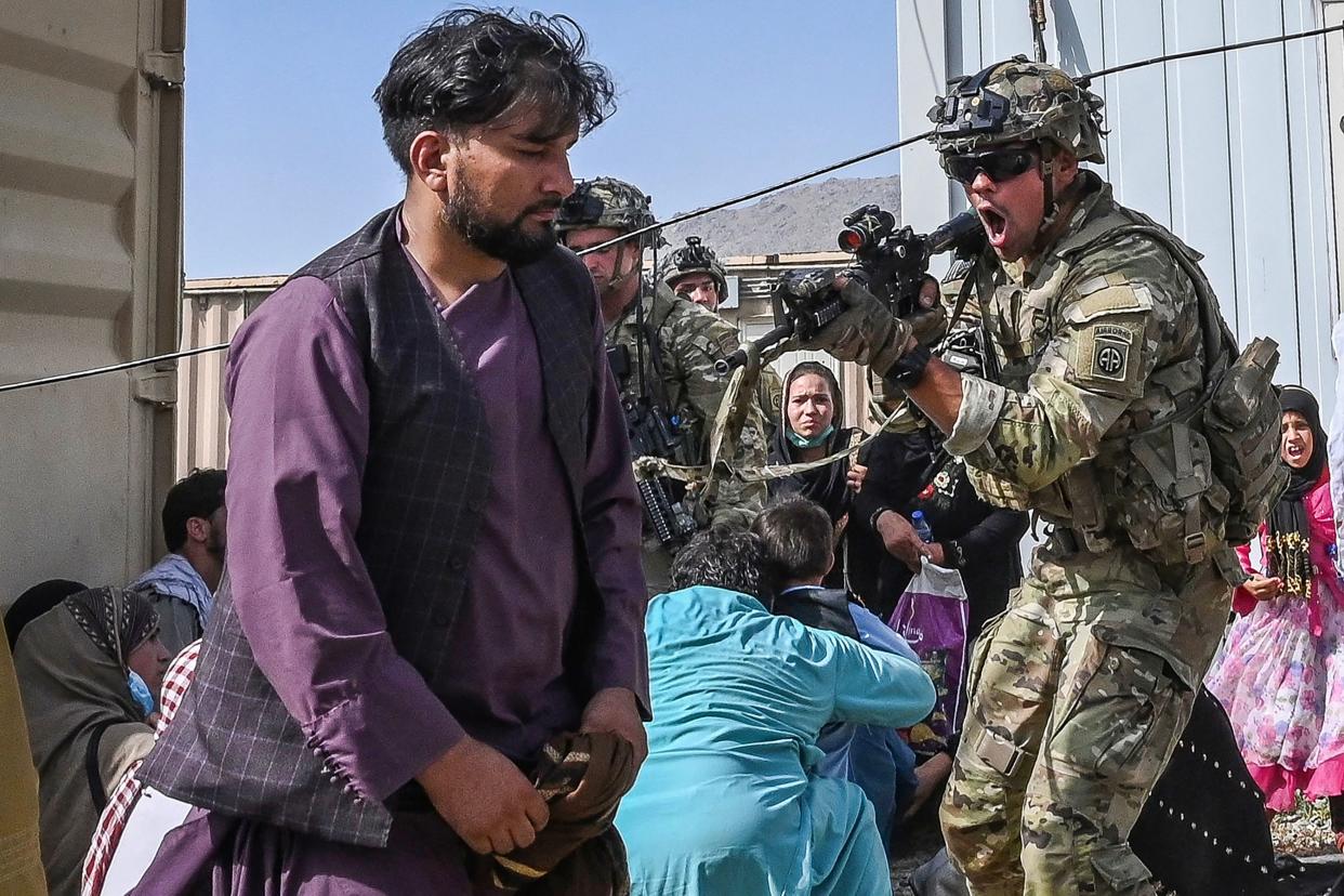 An American soldier points his gun at an Afghan at the airport in Kabul on Monday. 