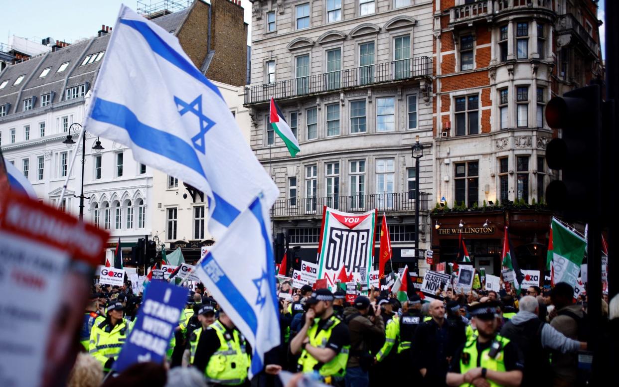 Police officers stand guard as demonstrators waving Israeli flags hold a counter protest opposite pro-Palestinian activists marching in central London on March 30 2024