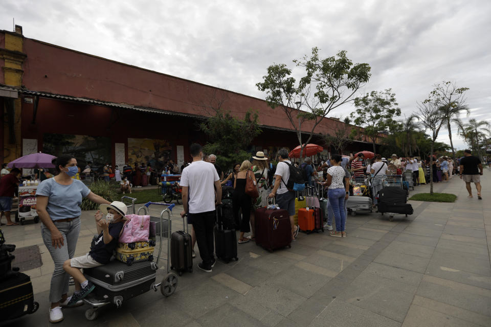 Passengers wait in line to board at the cruise ship 'MSC Preziosa'', in the Port Area of Rio de Janeiro, Brazil, Sunday, Jan. 2, 2022, after Brazil's Sanitary Agency has confirmed more cases of COVID-19 on board. Rio's Health Secretariat said that those living in the city or nearby regions will be quarantined in their homes. Those who live outside the state will be isolated in hotels. (AP Photo/Bruna Prado)