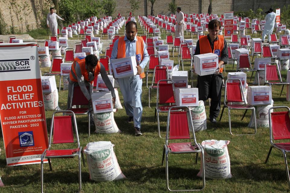 Volunteers from the religious charity group Al-Khidmat Foundation Pakistan arrange food and other items to be distributing to flood affected families, in Shabqadar near Peshawar, Pakistan, Tuesday, Sept. 13, 2022. The death toll from three months of record-breaking floods in Pakistan rose to over 1,400, officials said Tuesday, as the minister for climate warned the prolonged monsoon rains will continue lashing this impoverished nation in the coming weeks. (AP Photo/Muhammad Sajjad)