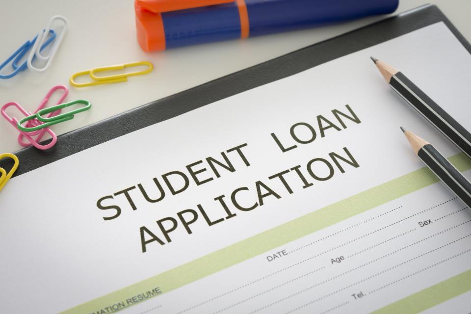 Student loan application with pencils and paperclips on top of it.