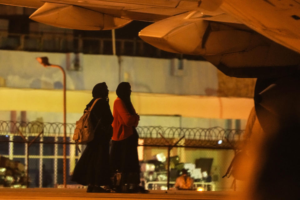 Sudanese evacuees wait under a pane at Port Sudan airport, Thursday, May 11, 2023. The conflict between the country's military and a rival paramilitary group has killed hundreds and displaced hundreds of thousands since it broke out in mid-April, creating a humanitarian crisis inside the country and at its borders. (AP Photo/Amr Nabil)