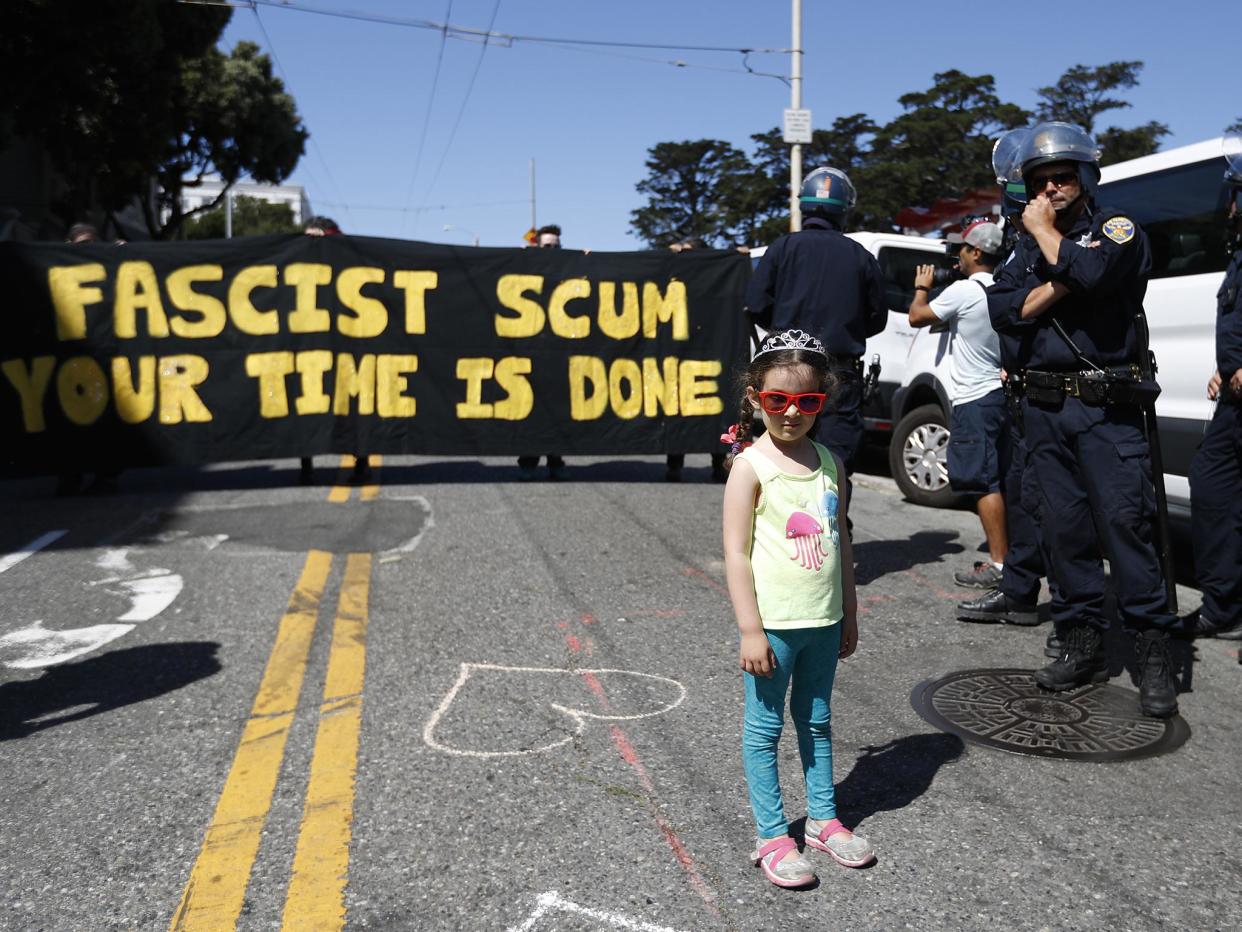 A young girl gets into the party spirit next to a line of police officers by Alamo Square after a rally expected to attract extremists, including the Ku Klux Klan, was called off: Getty Images