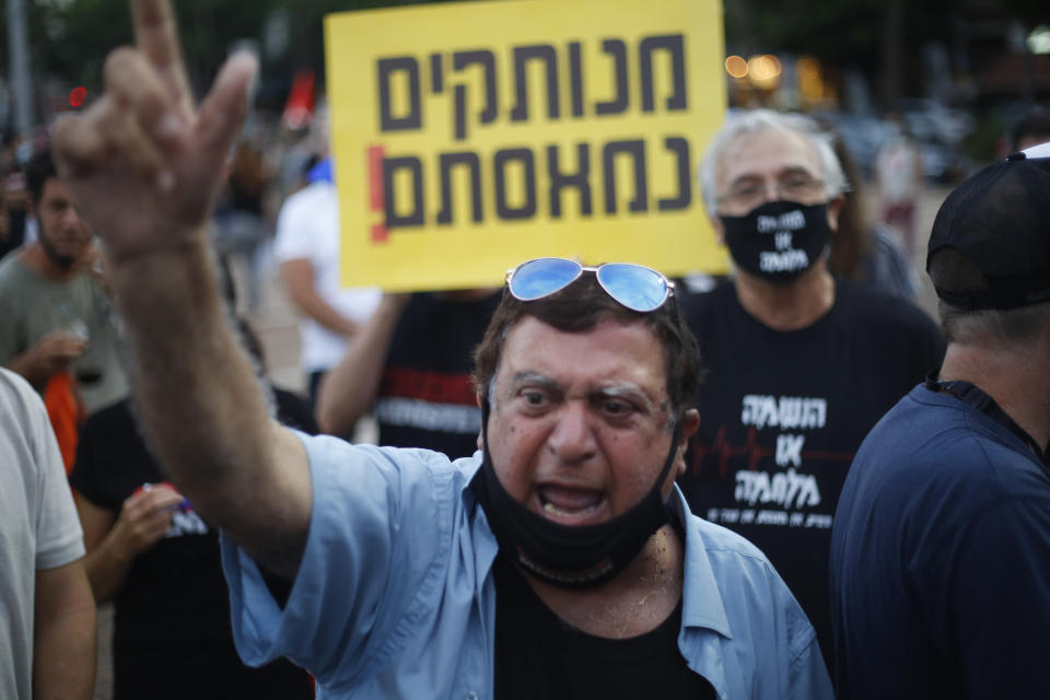 Protesters hold signs during a demonstration against Israel's government in Rabin square in Tel Aviv, Israel, Saturday, July 11, 2020. Thousands of Israelis gathered Saturday to protest the new government's failure to address economic woes brought by the coronavirus, directing their anger at Prime Minister Benjamin Netanyahu who is seeing his support plummeting. The signs say" "Out of touch. We're fed up."(AP Photo/Ariel Schalit)