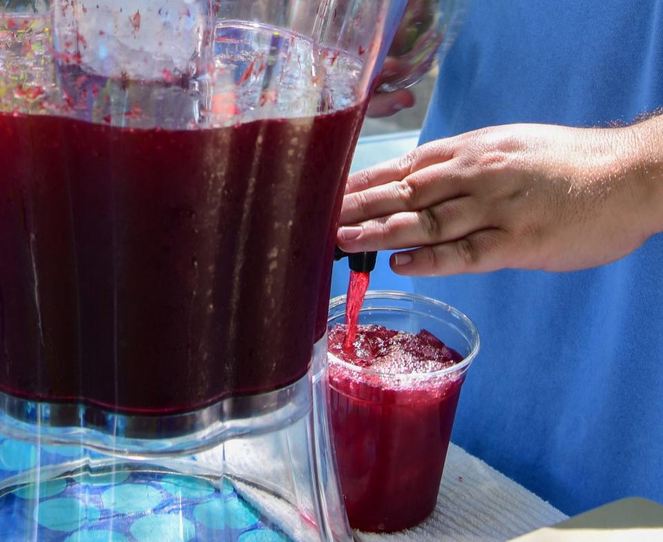 Travis Arnold of Aunt Polly's Farm pours a glass of homemade blueberry lemonade at the Downtown Hattiesburg Farmers Market.