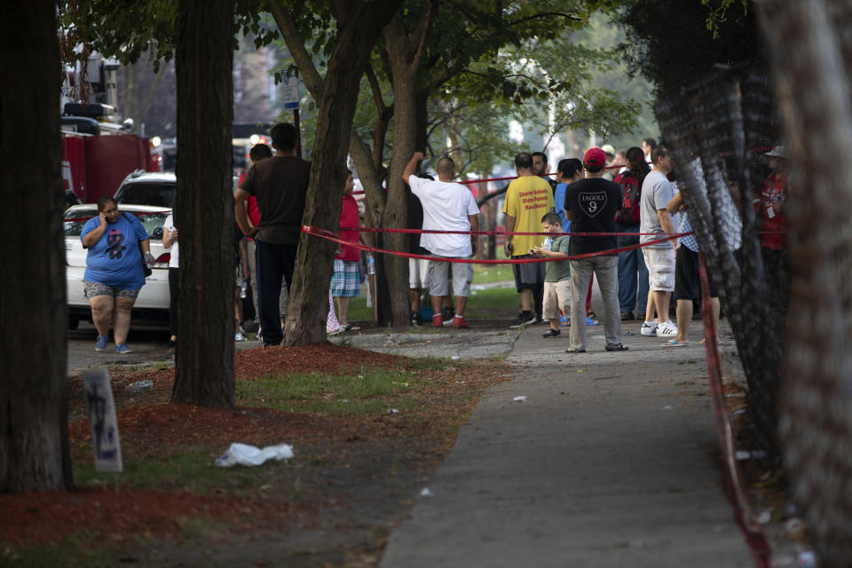 People stand around at the scene after a fire killed several people including multiple children Sunday, Aug. 26, 2018, in Chicago. The cause of the blaze hasn't been determined. (Erin Hooley/Chicago Tribune via AP)