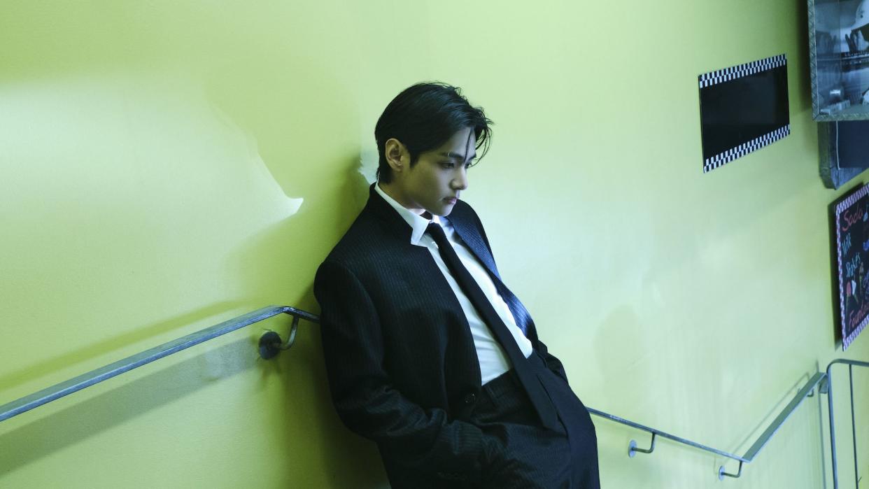 a person in a suit leaning against a wall