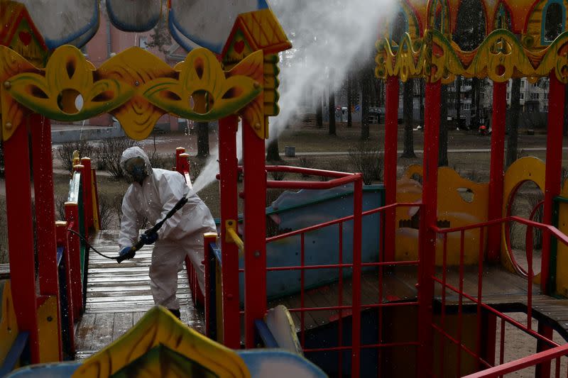 FILE PHOTO: A specialist wearing protective gear sprays disinfectant while sanitizing a playground in Vsevolozhsk