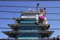 Helio Castroneves of Brazil climbs the fence at the start/finishing as he celebrates after winning the Indianapolis 500 auto race at Indianapolis Motor Speedway in Indianapolis, Monday, May 31, 2021. (AP Photo/Paul Sancya)