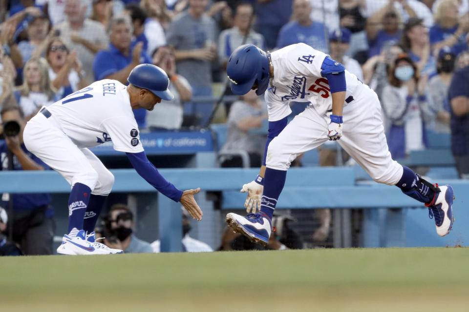 Los Angeles Dodgers' Mookie Betts, right, celebrates with third base coach Dino Ebel while rounding third after hitting a solo home run, his second homer of the baseball game, during the second inning against the Houston Astros in Los Angeles, Wednesday, Aug. 4, 2021. (AP Photo/Alex Gallardo)