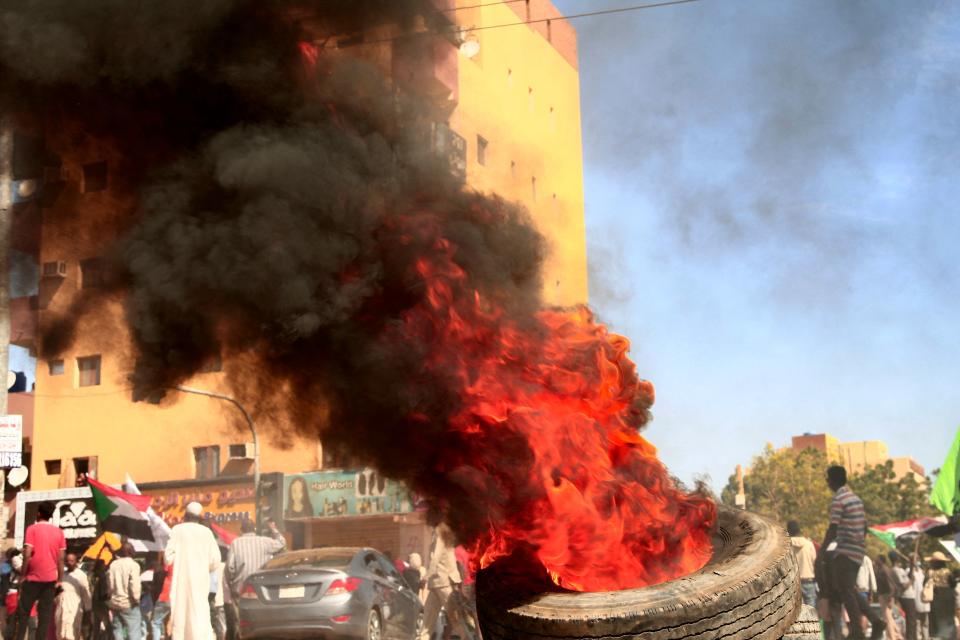 TOPSHOT - Sudanese protesters burn tires at the scene of confrontations with security forces in the capital Khartoum, on December 25, 2021, during a demonstration demanding civilian rule. Thousands of Sudanese protesters rallied two months after a military coup, demanding soldiers 