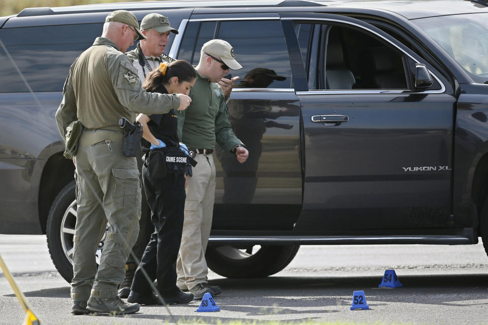 Law enforcement officials process a scene involved in Saturday's shooting, Sunday, Sept. 1, 2019, in Odessa, Texas. Bullet holes are visible near the car door handle. Authorities said Sunday they still could not explain why a man with an AR-style weapon opened fire during a routine traffic stop in West Texas to begin a terrifying rampage that killed several people, injured over a dozen others and ended with officers gunning him down outside a movie theater. (AP Photo/Sue Ogrocki)
