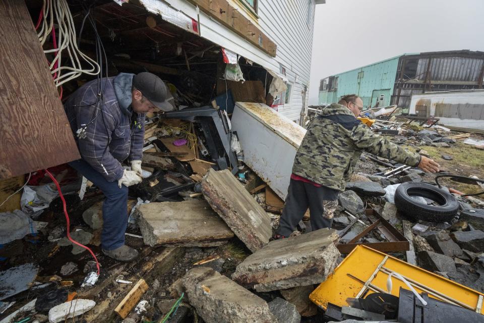 People clear out a damaged home in Burnt Island, N.L. following Hurricane Fiona in September 2022. THE CANADIAN PRESS/Frank Gunn