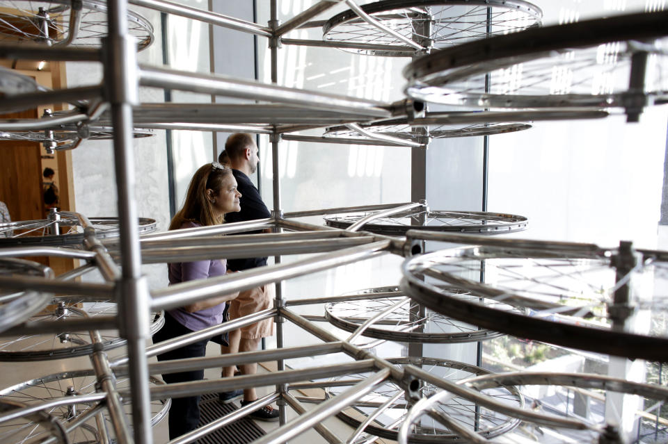 In this Saturday, Dec. 7, 2013 photo, museum goers view a piece titled "Stacked" featuring a maze of hundreds of bicycle wheels by the Chinese artist Ai Wei Wei at the Perez Art Museum Miami in Miami. The museum, called PAMM by locals, which opened in December, still lacks a permanent blockbuster, but its retrospective of Ai, on display through mid-March of 2014, should temporarily satisfy. (AP Photo/Lynne Sladky)