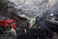 A firefighter walks past damaged shops at a tyre market after they were set on fire by a mob in a riot affected area after clashes erupted between people demonstrating for and against a new citizenship law in New Delhi