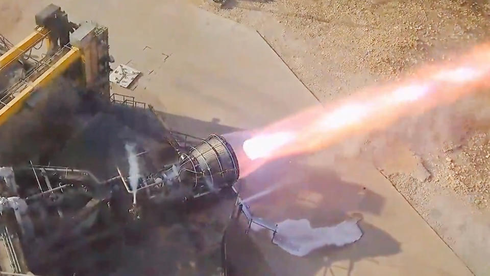 a long orange tail extends from a rocket engine during a test.