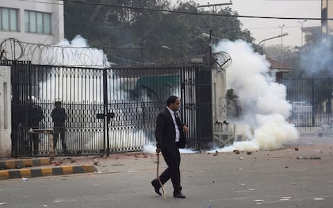 An angry lawyer runs for shelter after police fire tear gas shell to disperse them during a clash in Lahore, Pakistan, Wednesday, Dec. 11, 2019.  - Credit: AP