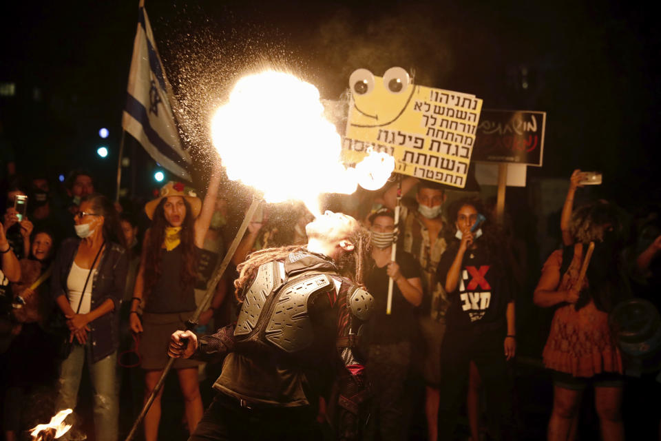 A performer dance with fire during a protest in front of Israel's Prime Minister's residence in Jerusalem, Thursday, July 16, 2020. Hundreds of protesters gathered outside Netanyahu's official residence in Jerusalem to protest against corruption and vent their anger at the economic downtown. (AP Photo/Ariel Schalit)