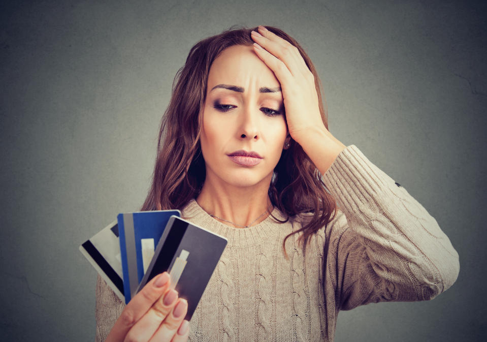 Woman looking at three credit cards with frustrated face