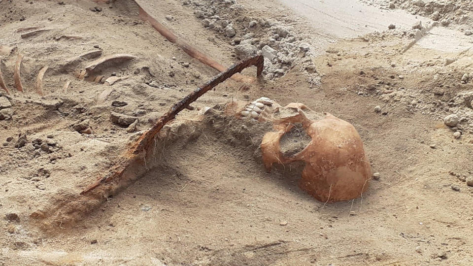 Skeletal remains of a woman with a sickle around her neck.