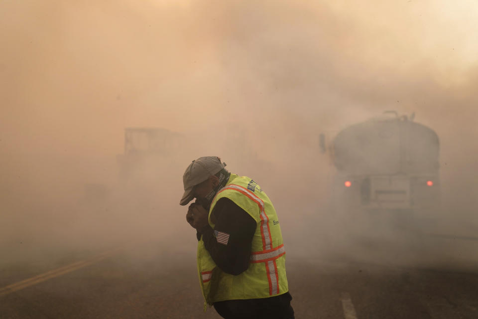 Len Brongo struggles with smoke from the Silverado Fire Monday, Oct. 26, 2020, in Irvine, Calif. A fast-moving wildfire forced evacuation orders for 60,000 people in Southern California on Monday as powerful winds across the state prompted power to be cut to hundreds of thousands to prevent utility equipment from sparking new blazes. (AP Photo/Jae C. Hong)