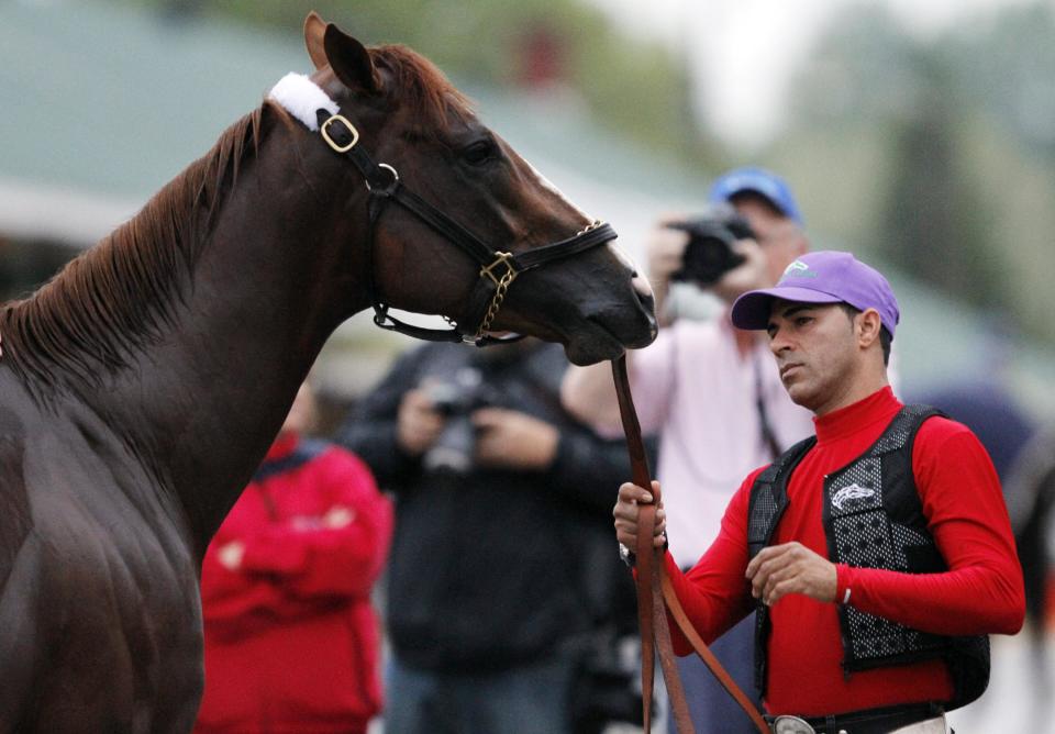 Exercise rider William Delgado holds Kentucky Derby hopeful California Chrome after a morning workout at Churchill Downs Tuesday, April 29, 2014, in Louisville, Ky. (AP Photo/Garry Jones)