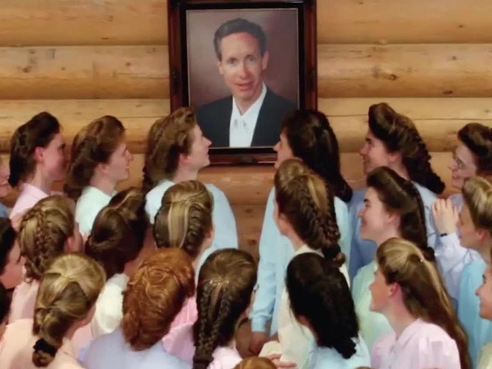 A group of FLDS women look at a photo of Warren Jeffs in "Keep Sweet: Pray and Obey."