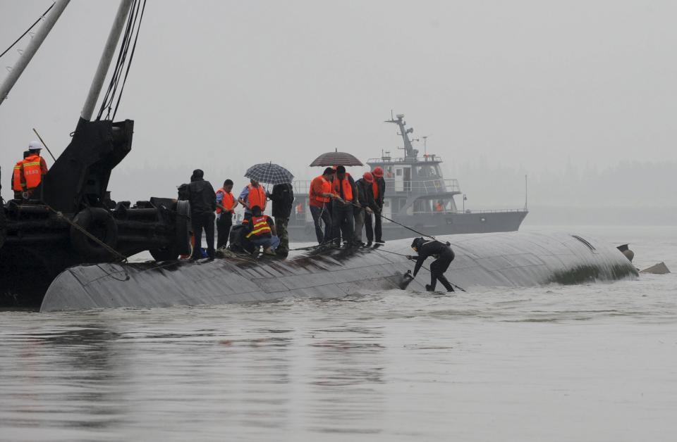 A diver (R) prepares to dive in the river to search for survivors after a ship sank at the Jianli section of the Yangtze River, Hubei province, China, June 2, 2015. Rescuers fought bad weather on Tuesday as they searched for more than 400 people, many of them elderly Chinese tourists, missing after a ship capsized on the Yangtze River. (REUTERS/China Daily)