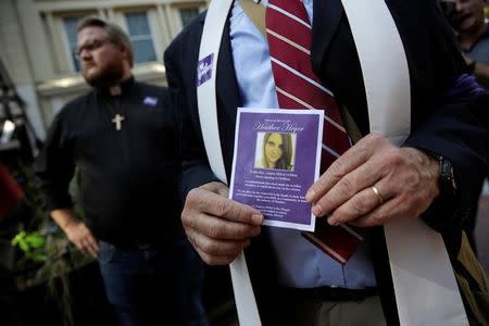 A member of the clergy holds a picture of Heather Heyer, who was killed at in a far-right rally, as they stand outside of her memorial service in Charlottesville, Virginia, U.S., August 16, 2017. REUTERS/Joshua Roberts NO RESALES. NO ARCHIVE.