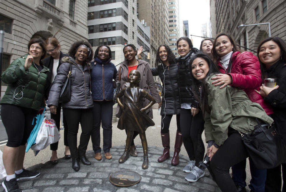 A group of women stop to pose with a statue of a fearless girl, Wednesday, March 8, 2017, in New York. The statue was installed by an investment firm in honor of International Women's Day. An inscription at the base reads, &quot;Know the power of women in leadership. She makes a difference. State Street Global Advisors.&quot; (AP Photo/Mark Lennihan)