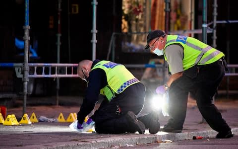 Policemen search the scene in Malmo  - Credit:  JOHAN NILSSON/AFP