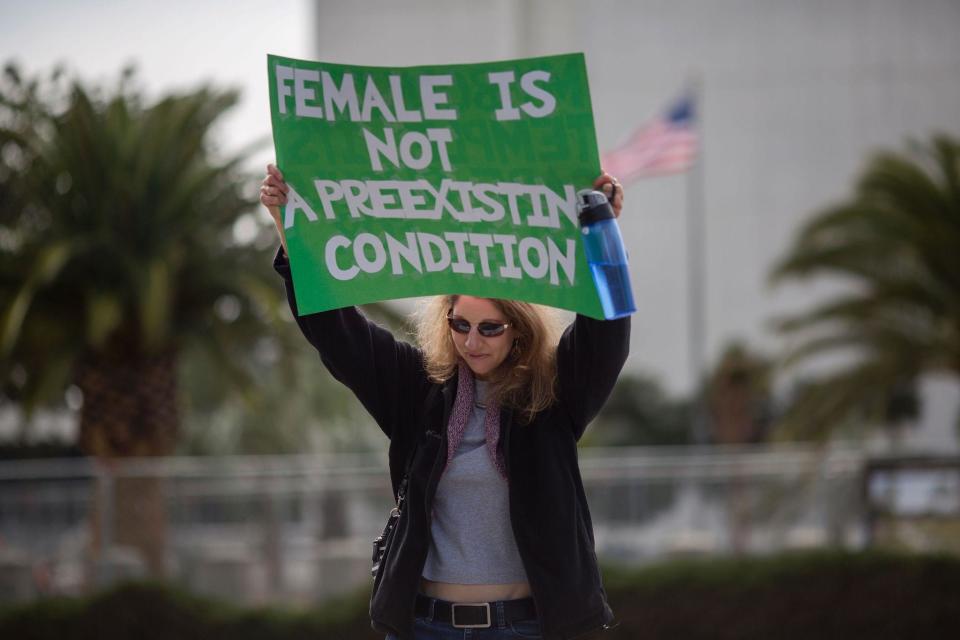 A woman holds a placard as people protest Trump administration policies that threaten the Affordable Care Act, Medicare and Medicaid: AFP/Getty Images