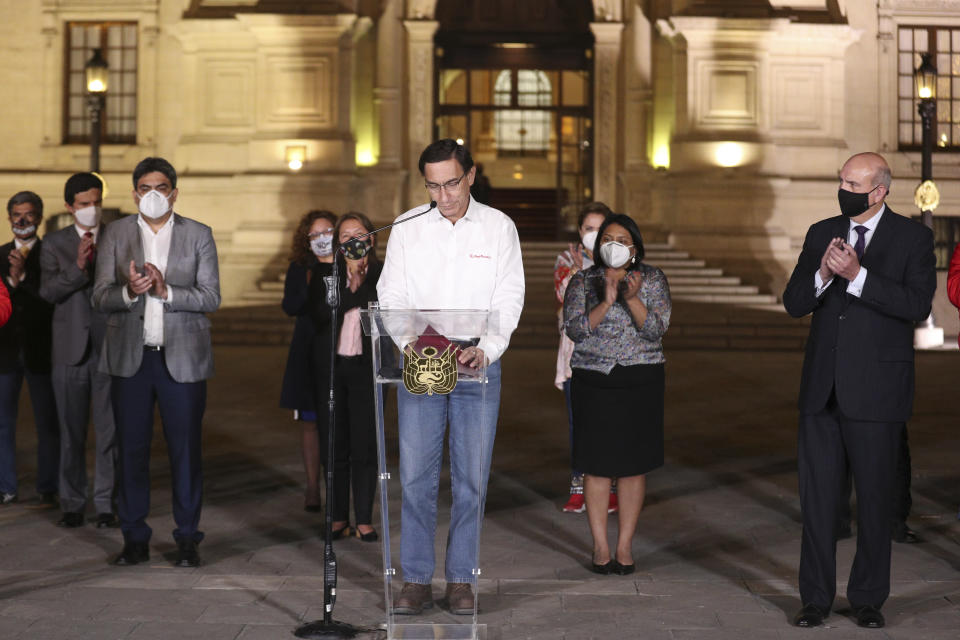 Peru's President Martin Vizcarra looks down as members of his cabinet applaud in front of the presidential palace after lawmakers voted to remove him from office in Lima, Peru, Monday, Nov. 9, 2020. Lawmakers voted overwhelmingly to impeach Vizcarra, expressing anger over his handling of the coronavirus pandemic and citing alleged but unproven corruption allegations. (AP Photo/Martin Mejia)