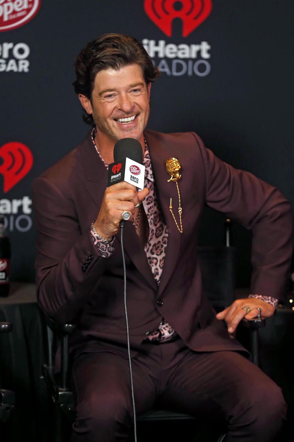 Thicke sitting and holding a mic, smiling