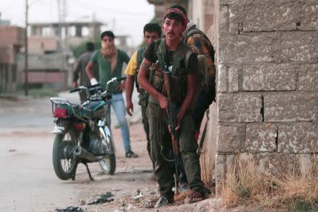 Kurdish fighters from the People's Protection Units carry their weapons as they take positions in the northeastern city of Hasaka, Syria. REUTERS/Rodi Said