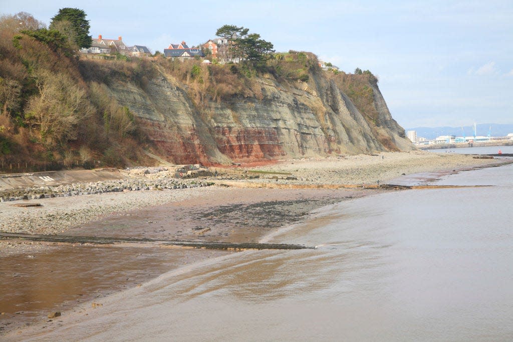 A beach in Wales with cliffs with red rocks and other rock types