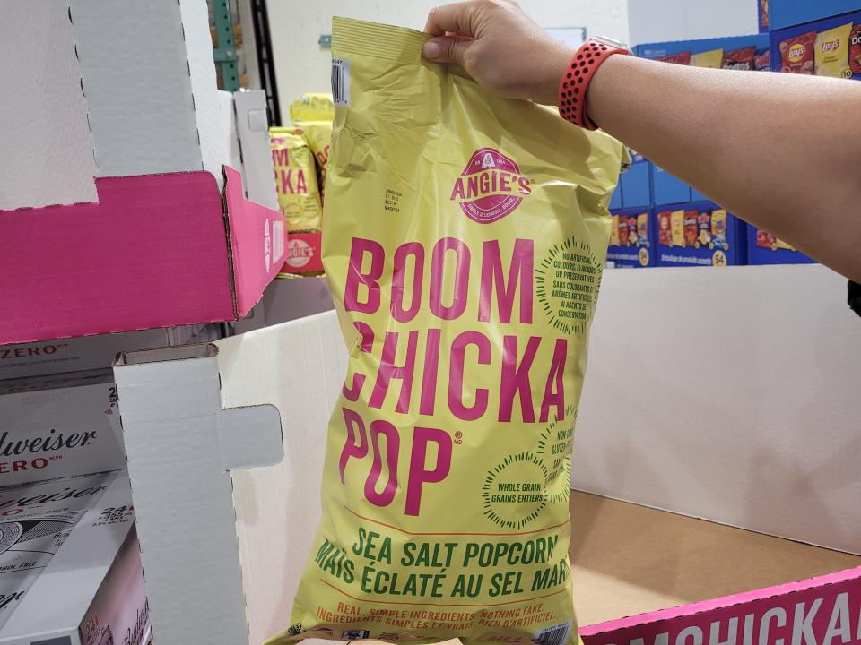 hand holding up a bulk bag of boom chicka pop popcorn at costco