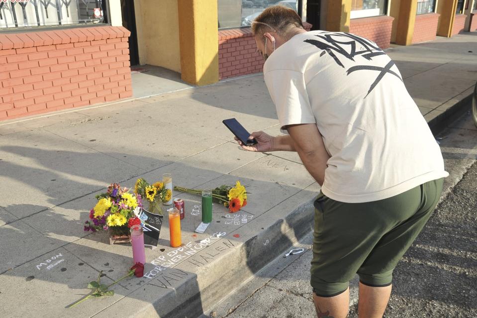 A fan of Eddie Van Halen photographs a makeshift memorial for Eddie near Van Halen's childhood home.