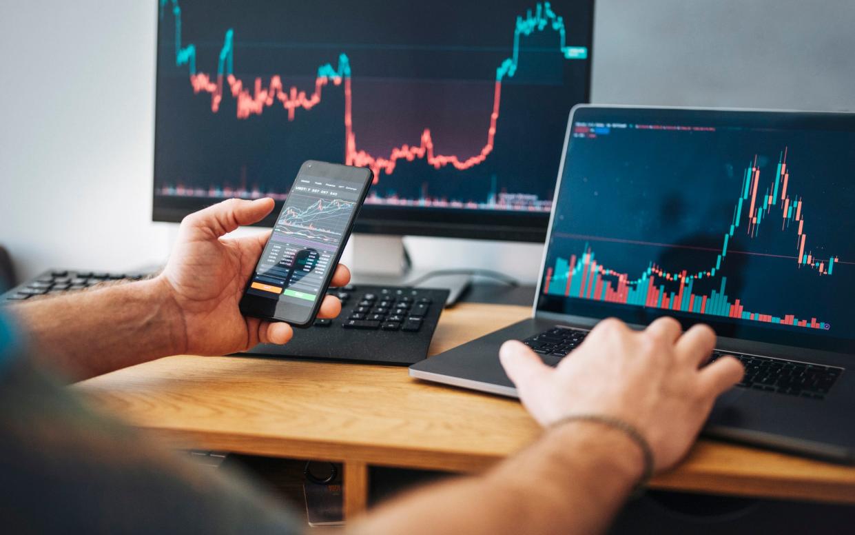 Man looking at currency trading app on his smart phone from his home office