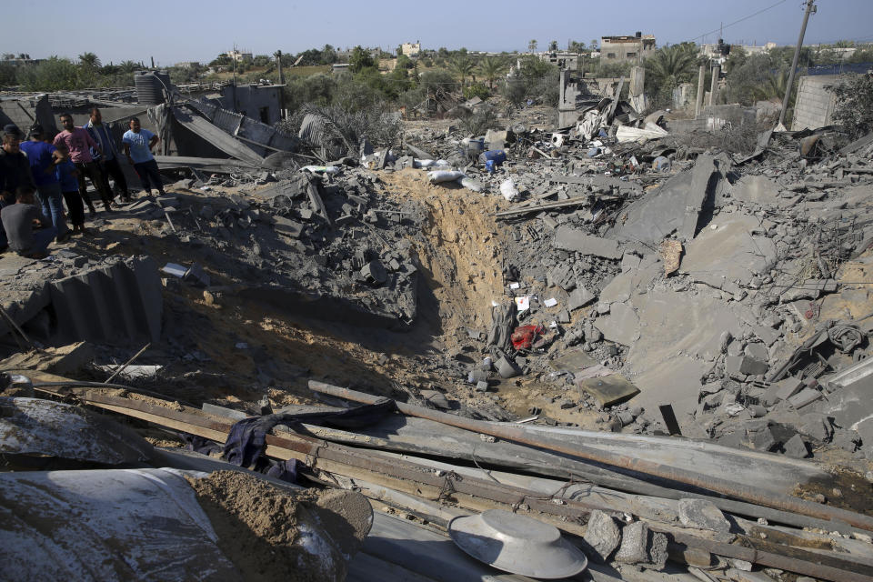 Palestinians inspect a crater and the rubble of destroyed houses following overnight Israeli missile strikes, in Al-Qarara, east of Khan Younis, southern Gaza Strip, Thursday, Nov. 14, 2019. (AP Photo/Adel Hana)