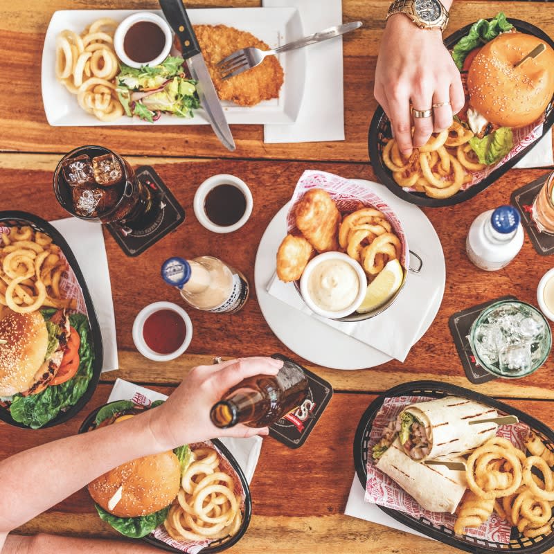 A table full of Hog's Breath meals, including burgers, wraps and their famous curly fries.