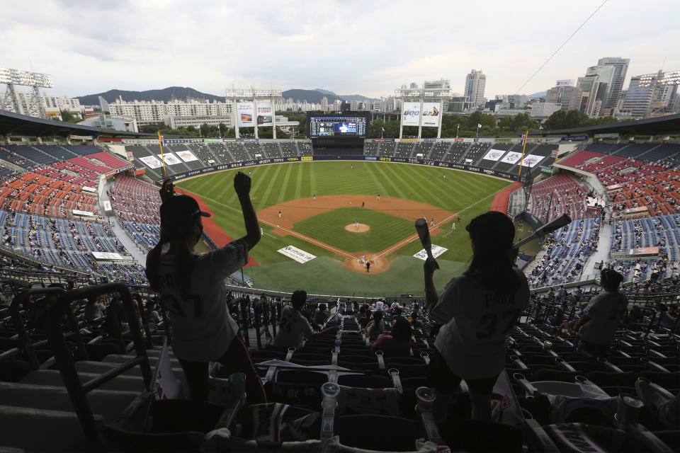 Fans wearing face masks to help protect against the spread of the new coronavirus cheer during the KBO league game between Doosan Bears and LG Twins in Seoul, South Korea, Sunday, July 27, 2020. Masked fans hopped, sang and shouted cheering slogans in baseball stadiums in South Korea on Sunday as authorities began bringing back spectators in professional sports games amid the coronavirus pandemic. (AP Photo/Ahn Young-joon)