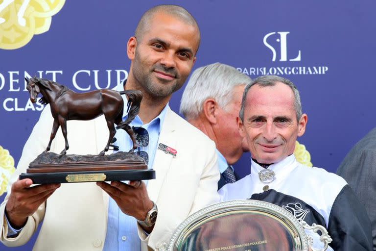 El ex compañero de Manu Ginóbili muestra el trofeo del triunfo de su potranca Mangoustine; a su lado, el jockey Gerald Mosse.