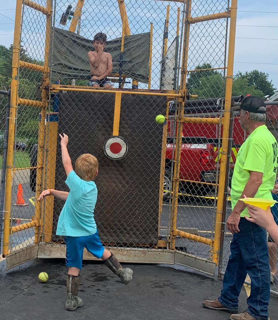 A youngster holds his nose in anticipation of falling into the water lying below him while sitting atop the dunk tank at the 2021 Knox Township Festival. The event will return this year on July 23.