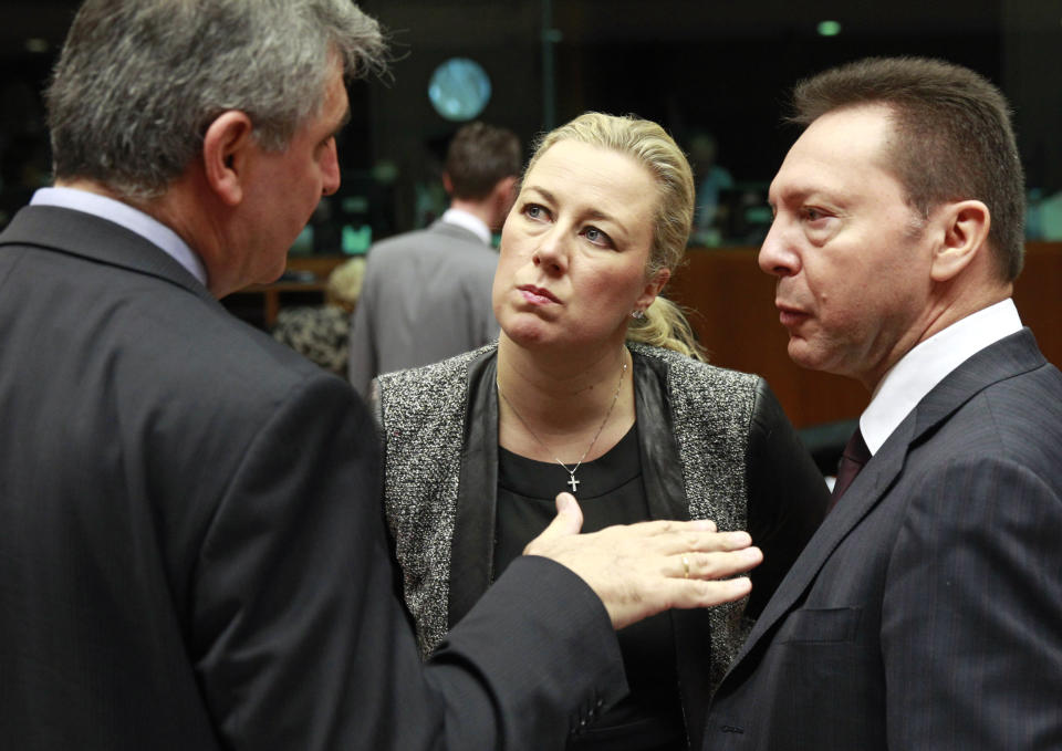 Greek Finance Minister and President of the rotating EU Council Yannis Stournaras, right, talks with Finnish Finance Minister Jutta Urpilainen, center, and an unidentified delegation member prior to the start of the EU finance ministers meeting at the European Council building in Brussels Tuesday, Feb. 18, 2014. (AP Photo/Yves Logghe)