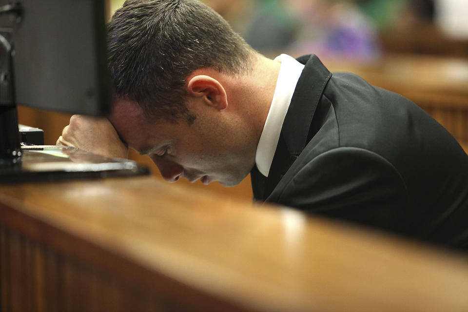 Oscar Pistorius places his head down while sitting in the dock in court on the third day of his trial at the high court in Pretoria, South Africa, Wednesday, March 5, 2014. Pistorius is charged with murder for the shooting death of his girlfriend, Reeva Steenkamp, on Valentine's Day in 2013. (AP Photo/Alon Skuy, Pool)