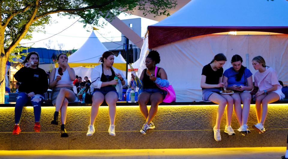 Festivalgoers sit on a wall to eat April 22, 2022, during the Festival of the Arts in downtown Oklahoma City.