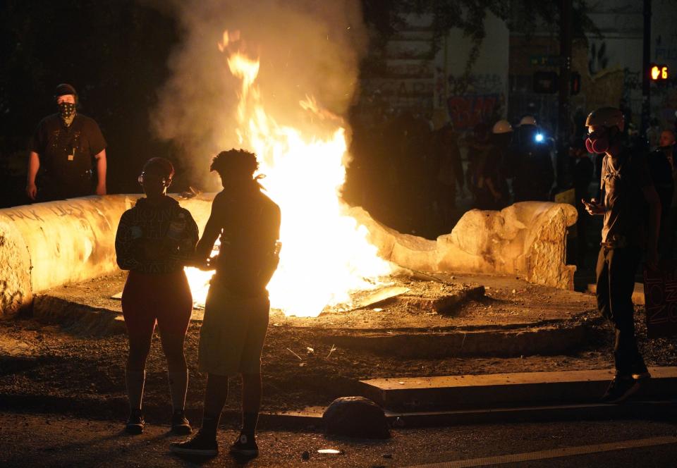 A fire illuminates people attending a protest at the Mark O. Hatfield Federal Courthouse in Portland, Oregon, on Monday night.